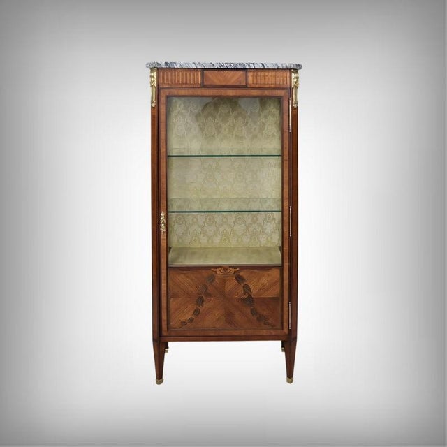 This three-sided display cabinet in mahogany and mahogany veneer, in the Louis XVI style, is a refined piece whose slender...