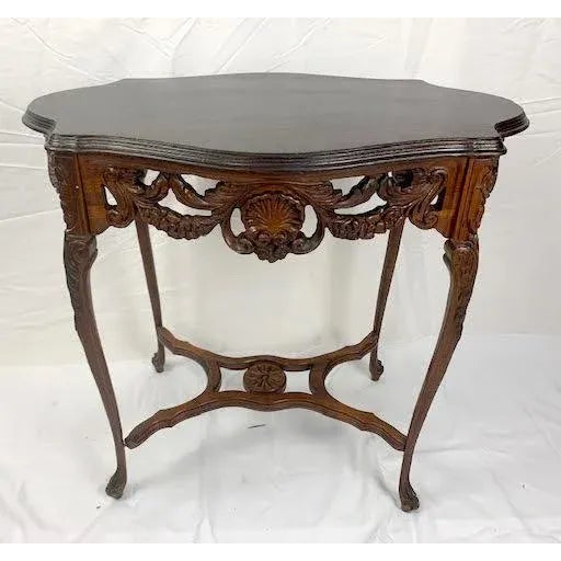Carved French style mahogany table with a carved skirt. Heavily carved apron with motifs of flowers, rocaille, and lily of...