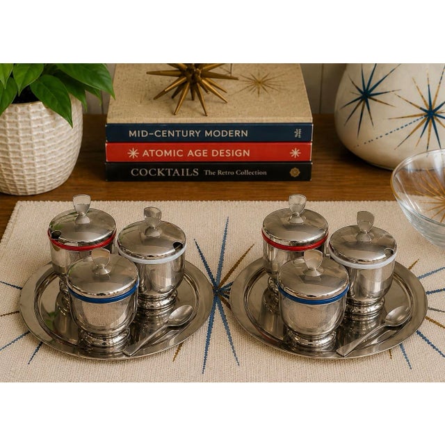 A charming pair of vintage Mid-Century Modern condiment serving sets featuring polished chrome-plated construction,...