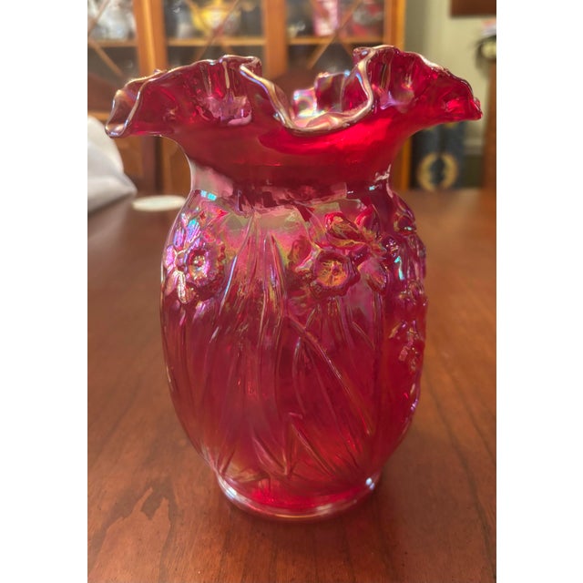 This is a beautiful red art glass vase by Fenton. The vase is decorated with embossed daffodils and has an iridescent...