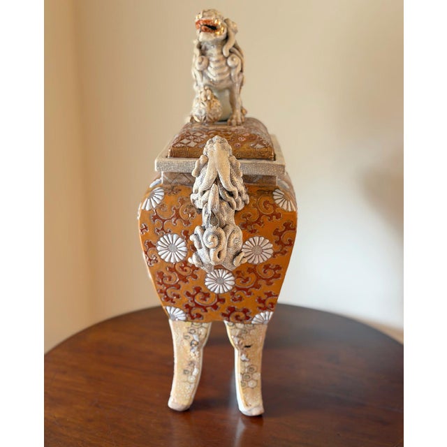 This is a decorative tripod censer-form vessel featuring a sculptural foo lion finial and matching mythical beast handles....