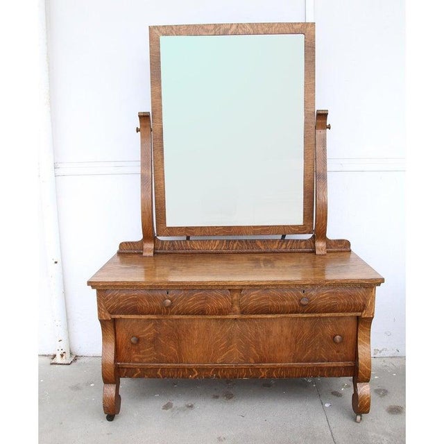 An exceptional antique carved tiger oak dresser with mirror. Three drawers. Castors. Measures: 52" W x 22.5" D x 77" H....