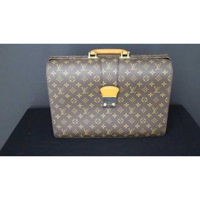 This highly original Louis Vuitton briefcase features monogrammed canvas and a brass lock. It also boasts a beautiful,...
