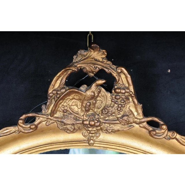 20th century beautiful oval wall mirror, gold. Oval framed wall mirror, gilded wood/stucco. Frame crowned with an eagle on...