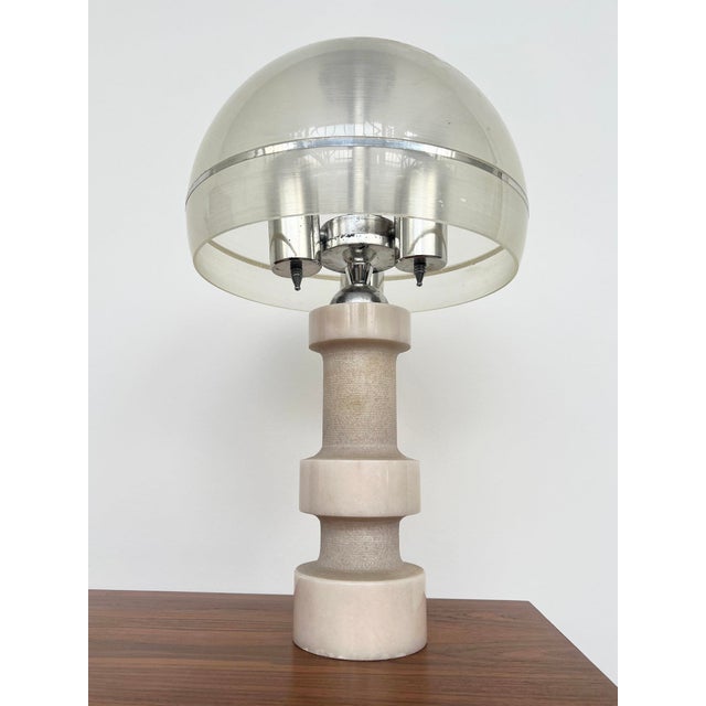 A stunning, sculptural table lamp with a turned marble base and a dome-shaped polycarbonate shade enhanced with chrome-...
