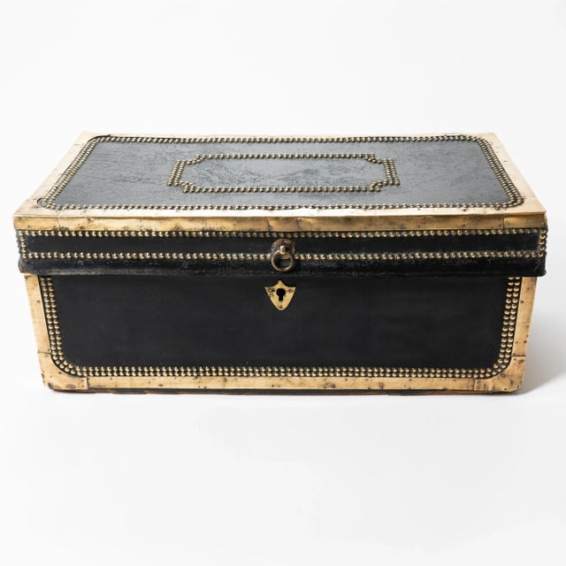 China trade brass bound black leather covered camphor wood trunk. The top and case are framed by brass corner mounts and...