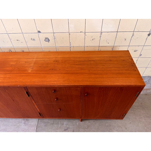 This vintage sideboard is crafted in warm teak veneer and features elegant wooden handles that perfectly complement its...