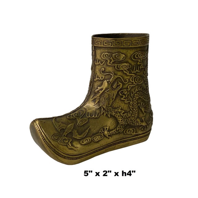 This is a Chinese boot shape Figure made of metal in a brown brass color with an engraved dragon bat motif on the surface...