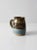 Vintage studio pottery mug featuring a generously sized hand-crafted form with a rich brown and blue glaze and a striking...