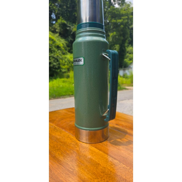 Iconic vintage Stanley green thermos with chrome accents and original folding handle. Classic American outdoor gear in...