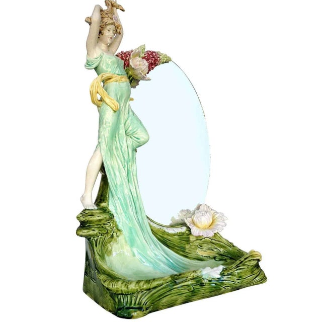 This oval vanity mirror is decorated with a large 23-inch ceramic female figure statue with Art Nouveau floral patterns. A...
