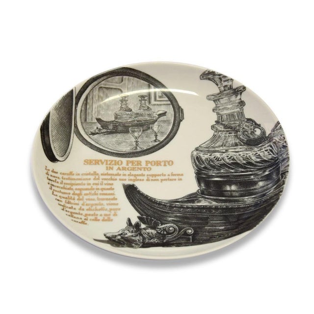 Servizio per Porto in Argento is a silk-screened porcelain plate, designed by Piero Fornasetti for Martini & Rossi in...