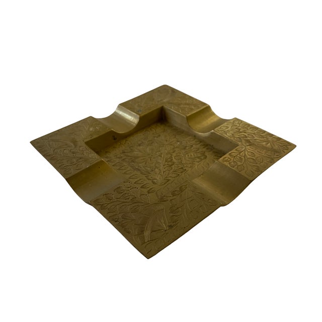 A striking vintage solid brass ashtray showcasing the fine hand-engraving and geometric styling characteristic of mid-...