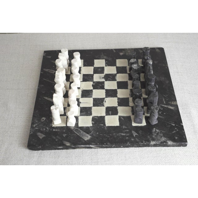 Marble chess board with white organic squares hand-painted onto surface, forming a subtle chess or checkerboard pattern,...