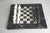 Marble chess board with white organic squares hand-painted onto surface, forming a subtle chess or checkerboard pattern,...