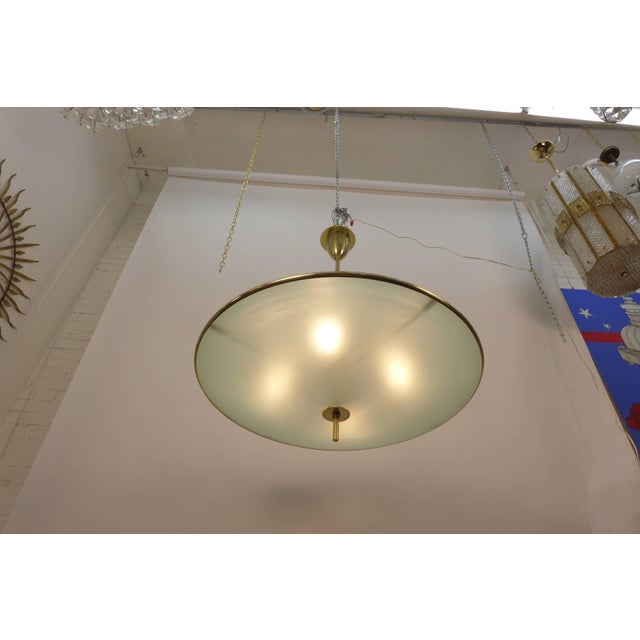 A very large pair of flying saucer chandeliers. They are made of solid brass and etched convex glass, each composed of two...