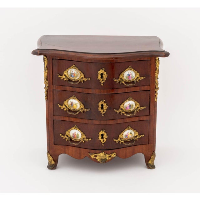 Louis XVI Style Porcelain and Gilt Metal Mounted Mahogany Diminutive Commode, the porcelain mounts hand-painted with...