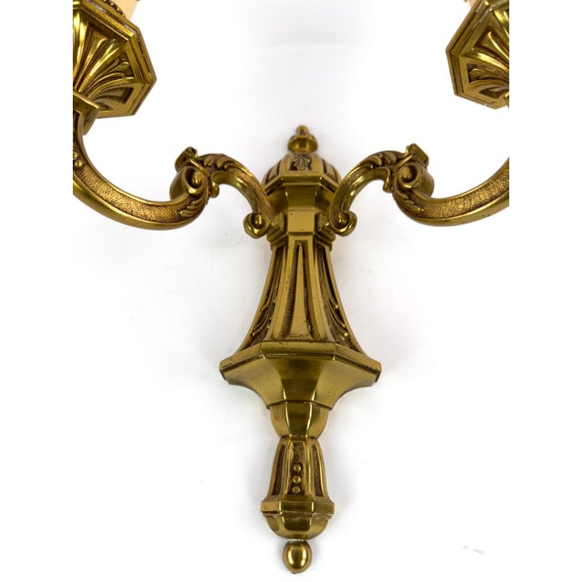 Vintage French brass two-arm wall sconce with elegant neoclassical detailing, likely dating from the mid-20th century. A...