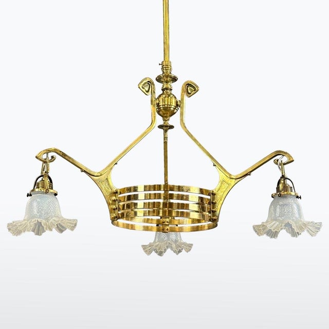 This Art Nouveau chandelier is a fine example of decorative lighting from around 1900. The solid brass structure features...