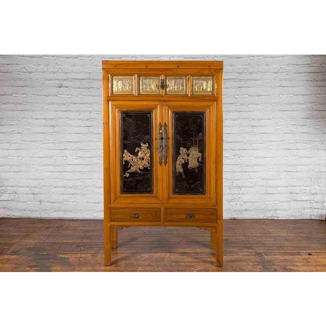 Early 20th century Chinese lacquered wood armoire with hand-carved gilt panels, doors and drawers. Created in the early...