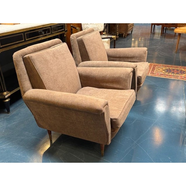 The product is a pair of vintage upholstered club chairs. These chairs feature a pale pink upholstery and clean lines. The...