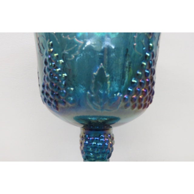 This wonderful iridescent blue goblet / cup is made of stunning carnival glass. It features the iconic Harvest Grape...