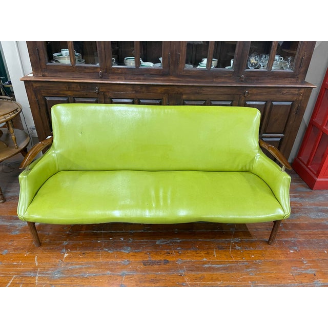 Striking mid-century modern sofa featuring a sculptural walnut frame, tapered legs, and organically curved seat in classic...