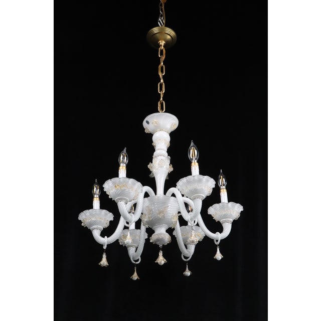 This six-arm Murano style glass chandelier is made from hand-blown opaque white glass with gold leaf inclusions. The...