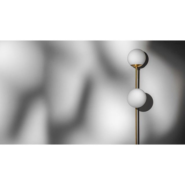 Offered by Schwung A pair of globes sit at right angles upon a brass sconce. Inspired by the design of classic brasserie...