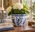 A classic blue and white porcelain planter, rendered in a softly faceted, scalloped form that feels both tailored and...