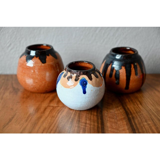 These three small, round, red-orange terracotta vases evoke something instinctive and warm, reminiscent of village pottery...