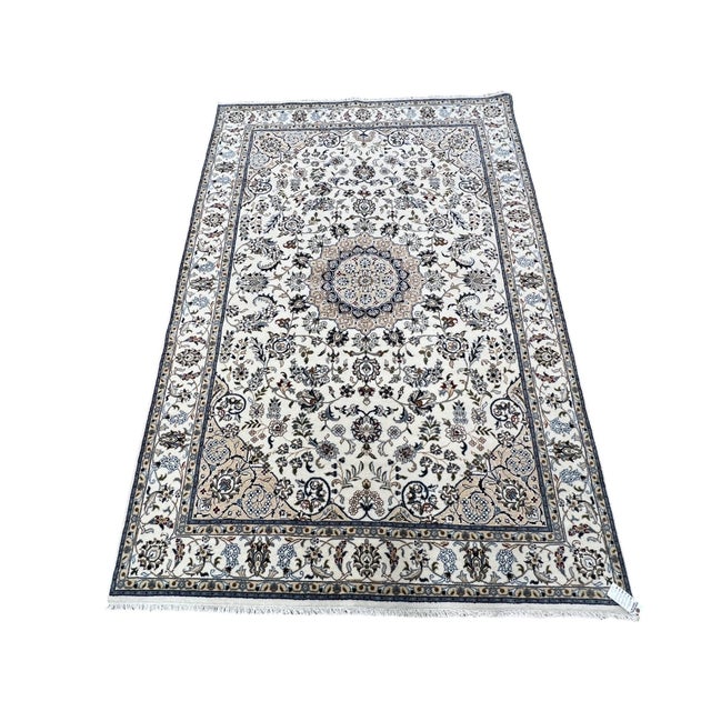 Persian Nain rug, hand knotted in India from 100% wool. Measuring 5’1” x 8’11”, the rug features an elegant traditional...