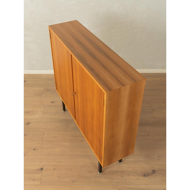 Beautiful chest of drawers from the 1960s. Walnut veneer body with two doors, two shelves, and new black square steel...