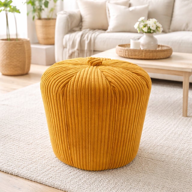 A compact Scandinavian pouf from the 1970s, featuring a cylindrical form and upholstered in mustard-colored corduroy...