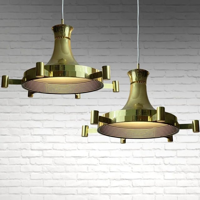 A pair of Swedish mid-century pendant lamps crafted by Fagerhults Belysning. Constructed from brass, they boast a...