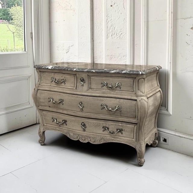 A 19th century Louis XV style bombe commode crafted from solid oak, revealed in a soft stripped finish that glows with the...