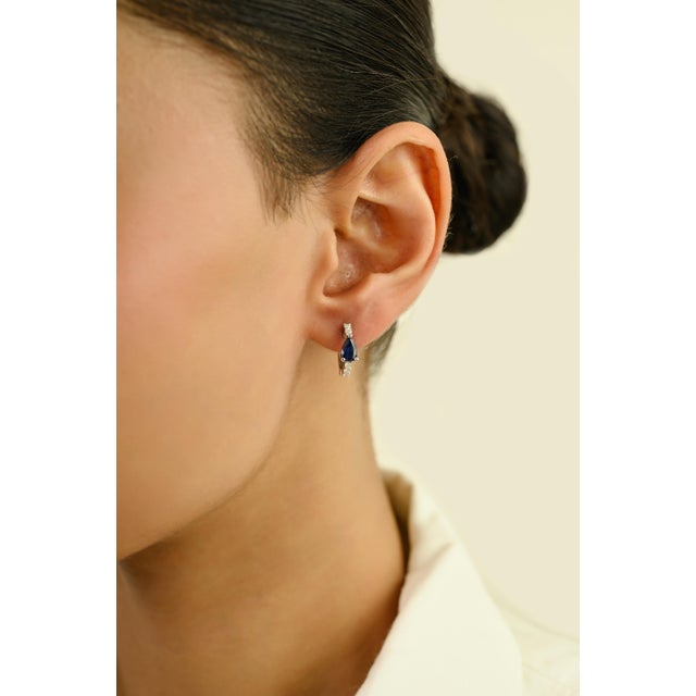 These elegant huggie hoop earrings feature 2 pear cut blue sapphires totaling 1 carat, set in rich 18k white gold. each...