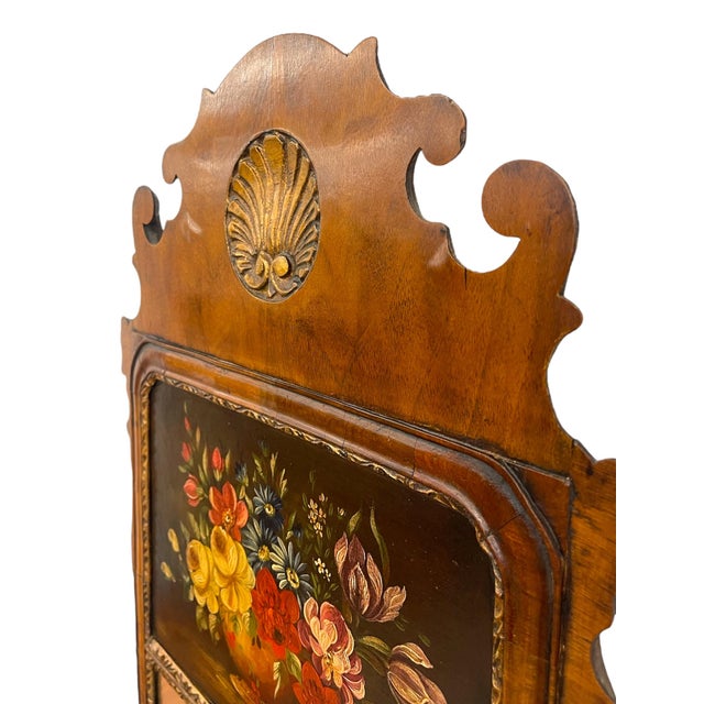 This English wall mirror features a classic Federal-style silhouette with an ornate scrolled crest and a carved shell...