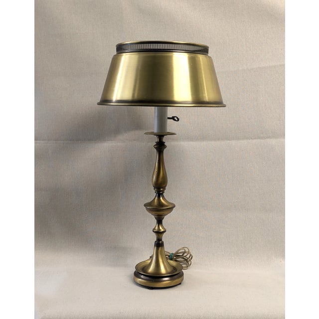 A striking brass bouillotte table lamp. The vintage library lamp has a brushed brass base with a bouillotte shade and...