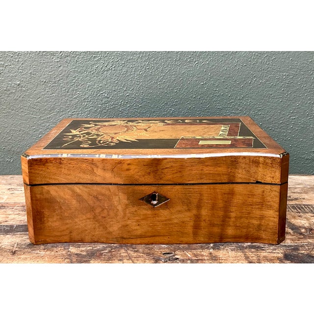 This vintage wood writing desk box showcases intricate inlay work, with floral and geometric marquetry set against a rich,...
