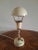 Lamp with double joints and hemispherical deflector. The lamp is made of brass, the brass is a lacquered cream color with...