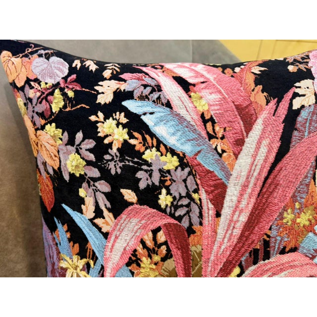 Large pink and turquoise tropical leaves rise from a deep black ground, surrounded by orange, gold, and mauve botanical...