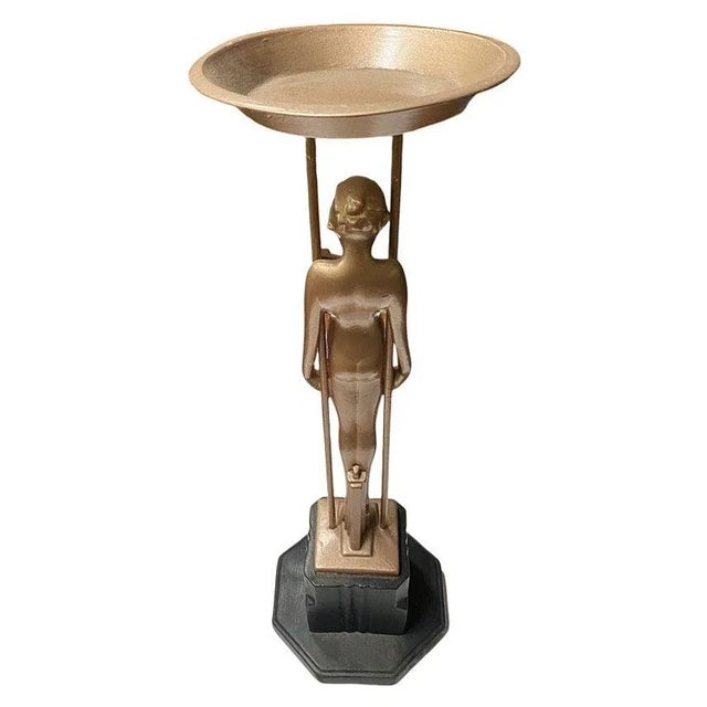 Frankart style Gold-tone figurative “Sarcophagus Girl“ metal ashtray stand featuring a nude women holding up the ashtray...
