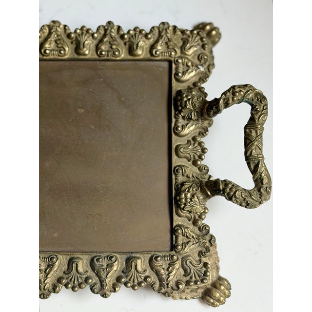 This vintage Victorian-style brass vanity tray features ornate detailing and decorative claw feet with a warm aged brass...
