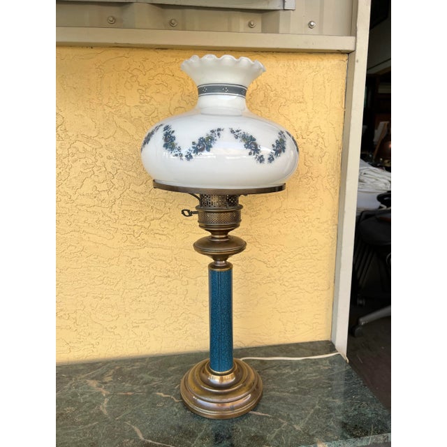 Vintage toleware blue lamp. White milk glass shade with decorative wave of small blue flowers and a thick blue band around...