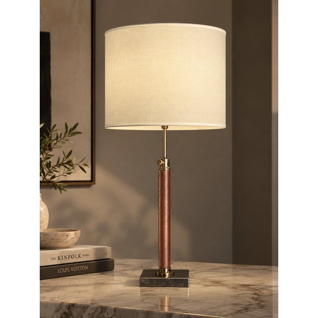 Table lamp with a slender rose-bronze textured column on a polished chrome-tone square base, topped with a broad cream...