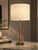Table lamp with a slender rose-bronze textured column on a polished chrome-tone square base, topped with a broad cream...