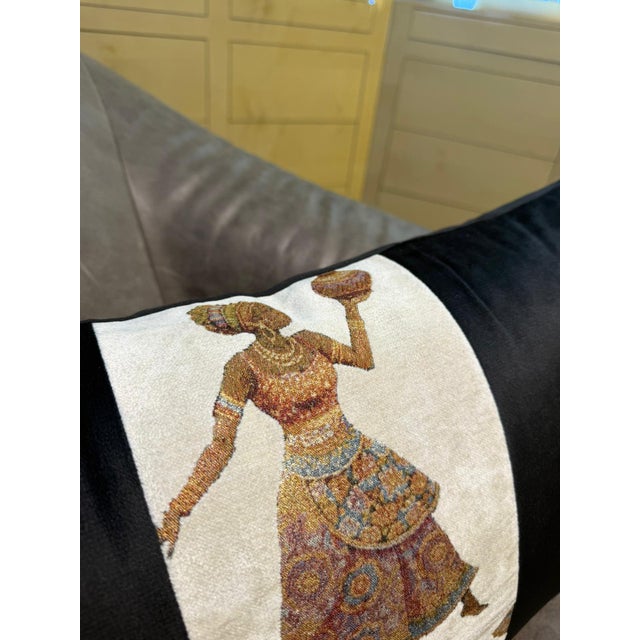 Two woven figures, stacked in a cream-ground jacquard center strip: above, a woman mid-movement in a boldly patterned...