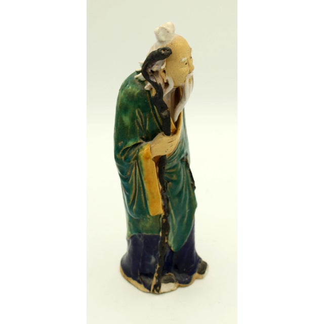 1892-1904 large Chinese mud man figure, an elder with staff in flowing green & yellow robe. Stamped "China". Apparent...