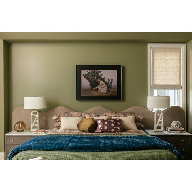 This oil painting depicts a serene scene featuring a woman kneeling beside a prickly pear cactus, gently reaching for...